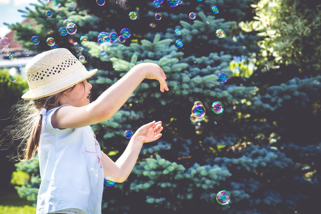 A child laughing in delight as soap bubbles float around them