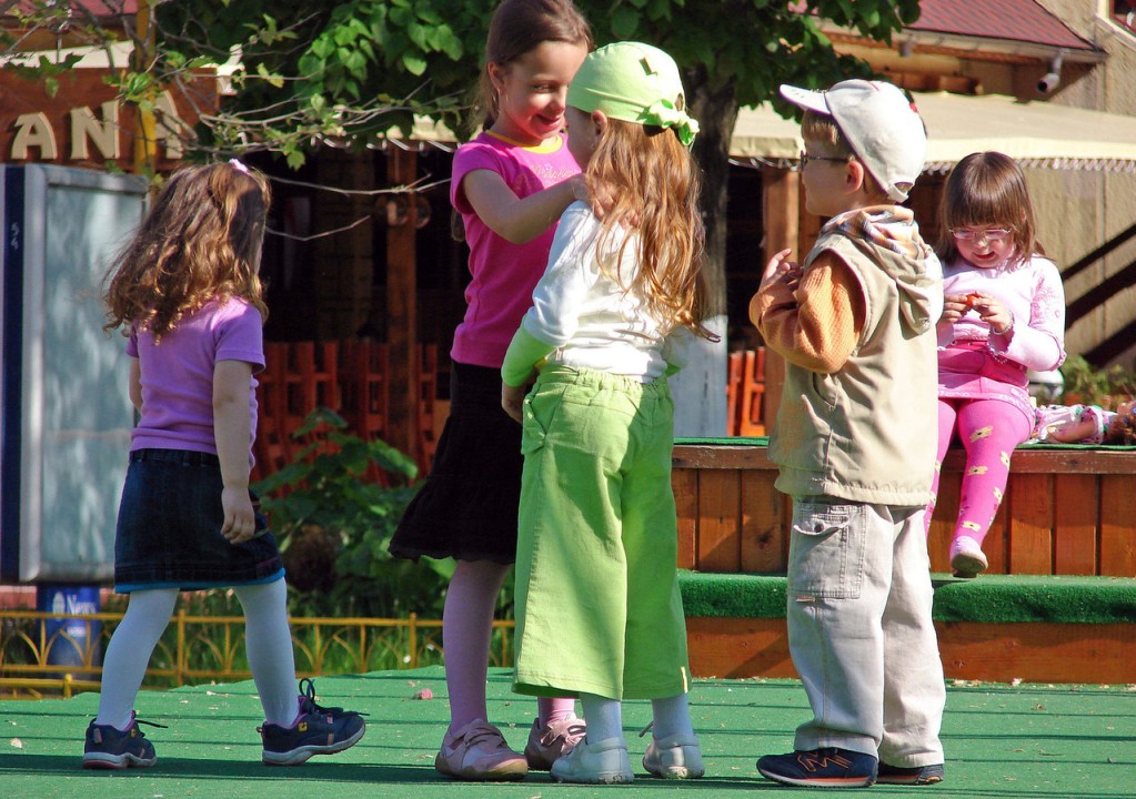 Children waving and smiling at each other from a distance