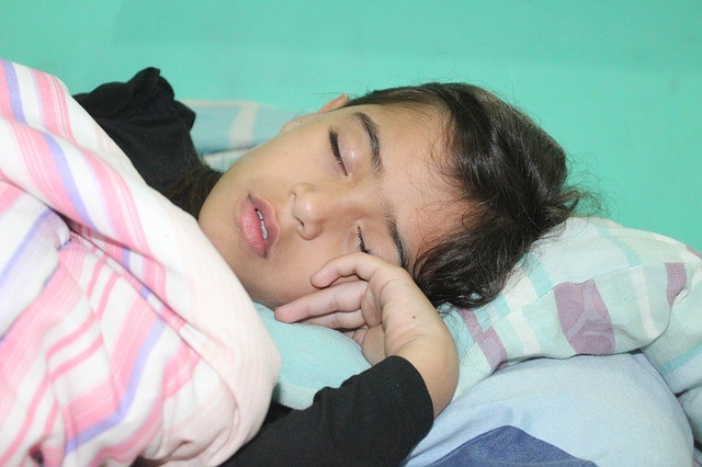 A peaceful child asleep in soft, dim bedroom light
