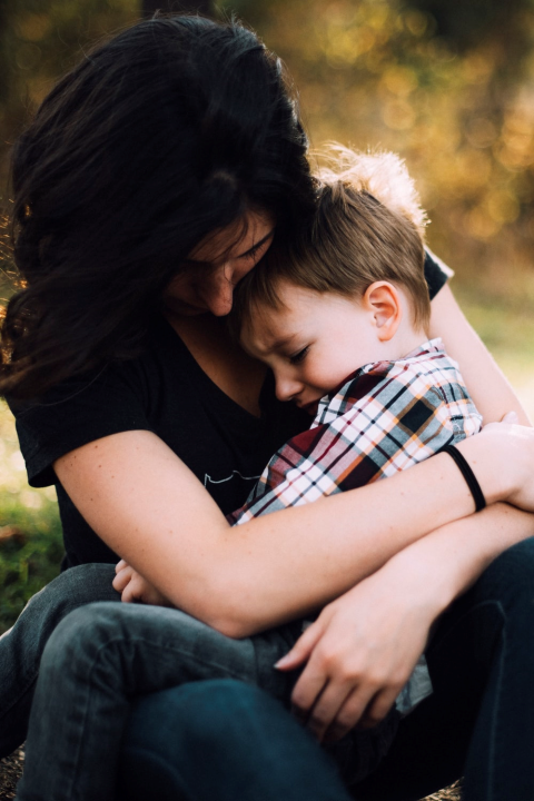 A parent gently holding a child's hand — a tender, quiet moment of comfort